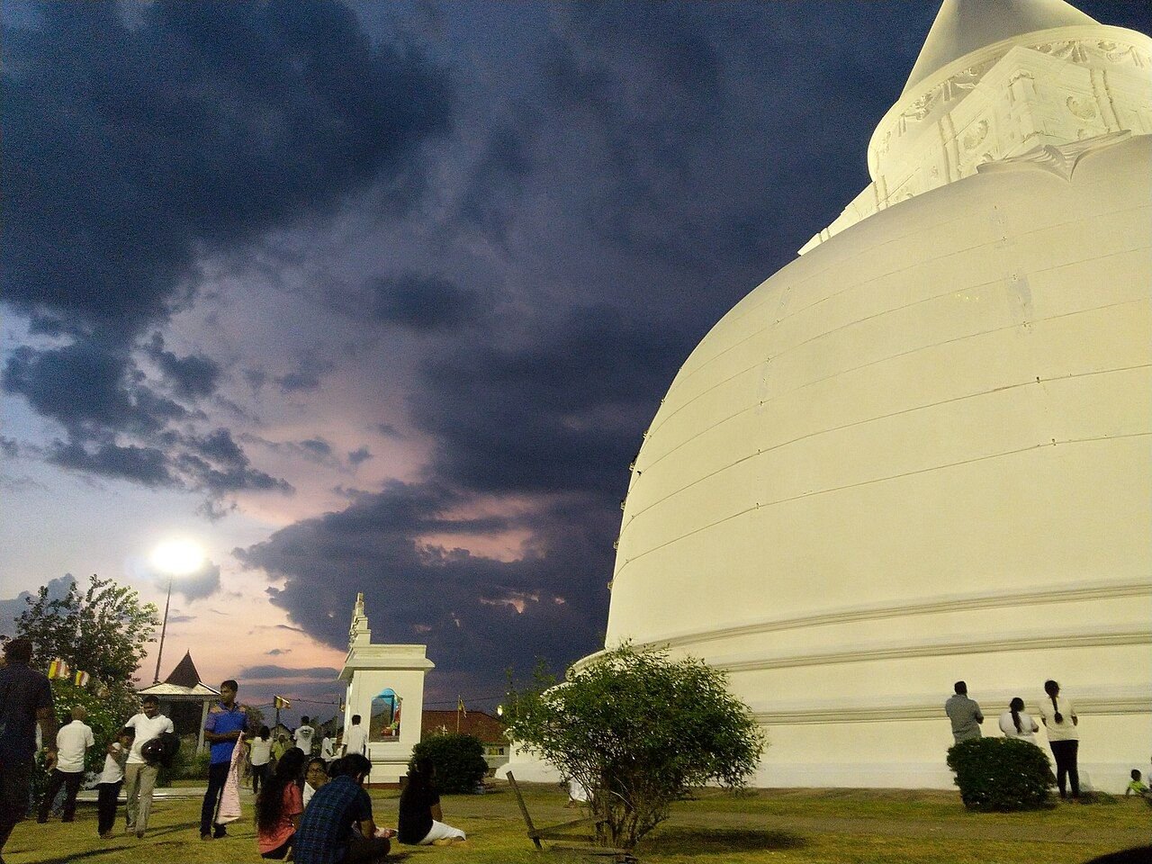 The stupa at dusk, with pilgrims at the foot of it for scale. 156 feet high and 550 feet around.