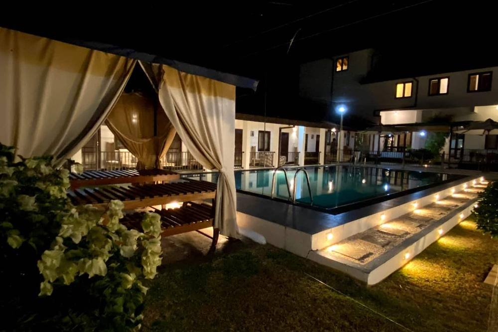 The villa's pool and verandah lit at night, Nainamadama